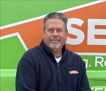 Jason standing in front of a vehicle with a logo behind him